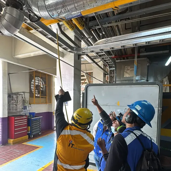 Técnicos de iT Power Systems inspeccionando instalaciones aéreas en un cuarto de máquinas