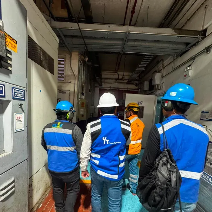 Personal de iT Power Systems recorriendo un cuarto eléctrico con tableros de distribución