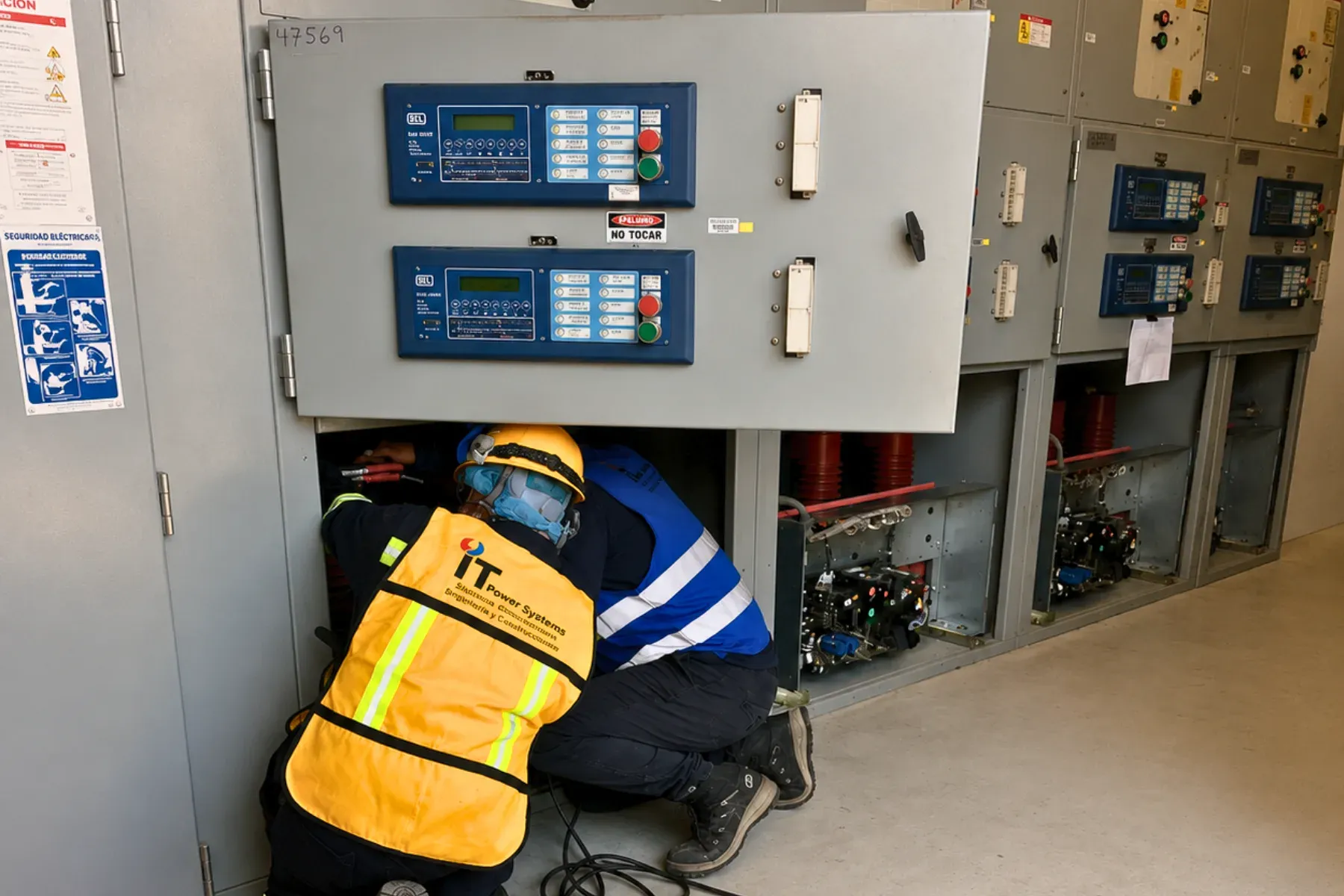 Dos técnicos de iT Power Systems probando los interruptores extraíbles de una línea de celdas de media tensión, con los interruptores de vacío visibles en los compartimentos
